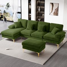 a living room with a large green couch and footstool on the rug in front of it