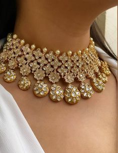 a close up of a woman wearing a gold necklace and choker with diamonds on it