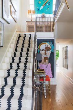 the stairs in this house are decorated with black and white geometric designs, while an abstract painting is on the wall