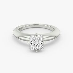 a white gold ring with an oval cut diamond in the center, on a plain surface