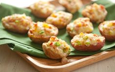 small appetizers are sitting on a wooden tray with green napkins and cloth