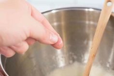 a person stirring something in a pot with a wooden spoon