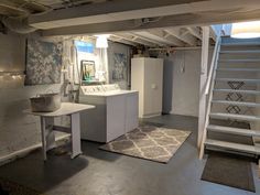 a room with a sink, refrigerator and stairs leading up to the second floor area