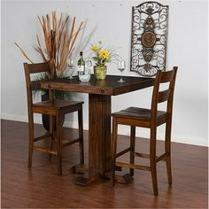 a wooden table with two chairs and a vase on it next to an iron screen