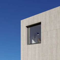 an open window on the side of a concrete building with a blue sky in the background