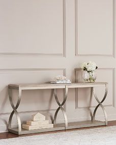 a console table with flowers and books on it in front of a white wallpapered room