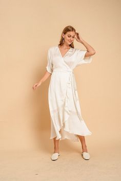 a woman wearing a white dress and slippers standing in front of a beige background