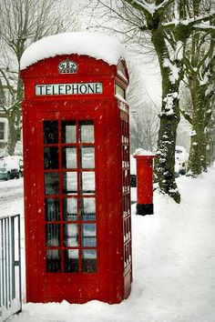 a red phone booth is covered in snow