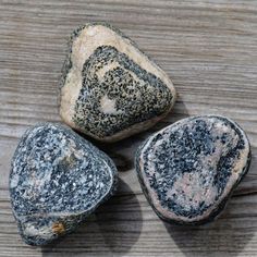 three black and white rocks sitting on top of a wooden table next to each other