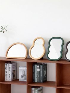 three mirrors sitting on top of a book shelf next to a vase with flowers in it