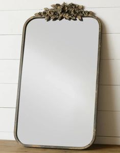 a large mirror sitting on top of a wooden table next to a white brick wall