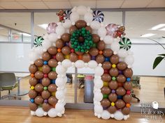 an arch made out of balloons in the shape of a house on a wooden floor