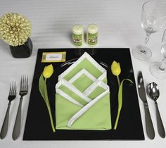 a place setting with green napkins and silverware