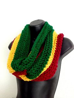 a black mannequin head wearing a green, yellow and red knitted scarf