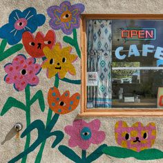 a painted wall with flowers and the words open cafe on it