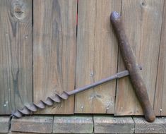 an old rusty wrench leaning against a wooden fence with nails sticking out of it