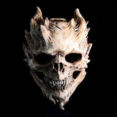 a creepy looking mask with horns and fangs on it's face, against a black background