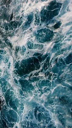 an aerial view of the ocean waves and rocks