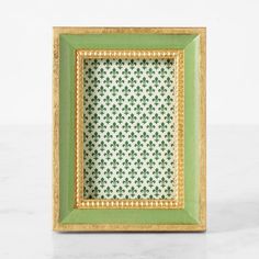 a green and gold frame sitting on top of a white counter