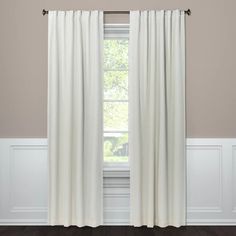 a white curtain hanging on the side of a window in a room with hardwood floors