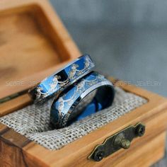 two wedding rings sitting on top of a wooden box