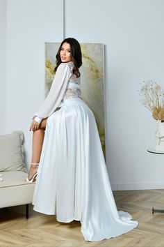 a woman sitting on top of a couch in a long white dress and high heels