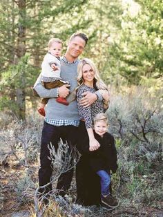 a man, woman and two children posing for a photo in the woods