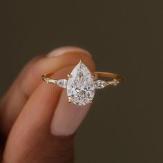 a woman's hand holding an engagement ring with two pear shaped diamonds on it