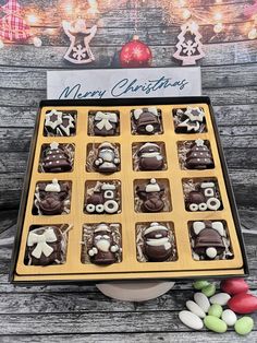 an assortment of chocolates in a box with christmas decorations on the table next to it