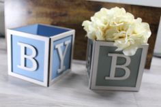 two blocks with flowers in them sitting on a table next to another block that says bly