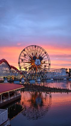 a ferris wheel sitting next to a lake at sunset