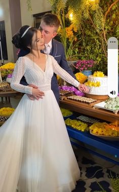 a man and woman are standing in front of a table with flowers on it, holding hands