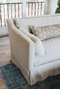 a white couch sitting on top of a wooden floor next to a rug and window