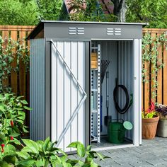 a garden shed with its doors open and gardening tools in the storage area next to it