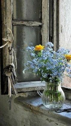 a vase filled with flowers sitting on top of a window sill next to a key