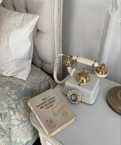 an old fashioned telephone sitting on top of a table next to a book and pillow