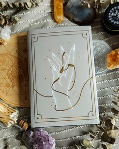 an open book sitting on top of a table next to crystals and other things around it