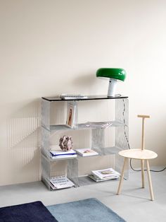 a shelf with books, magazines and a lamp on it next to a chair in a room