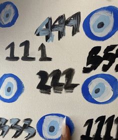 someone is painting numbers on a canvas with blue and black paint that looks like eyeballs