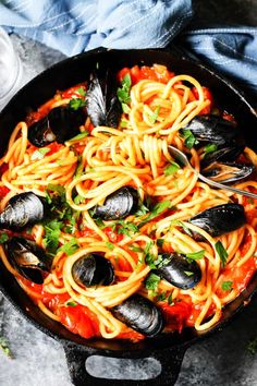 a skillet filled with spaghetti and mussels