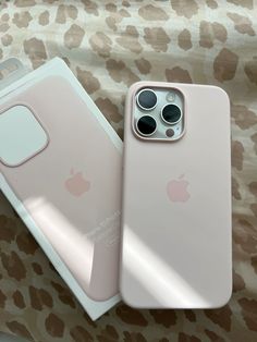 two iphones are sitting next to each other on a leopard print surface, one is pink and the other is white