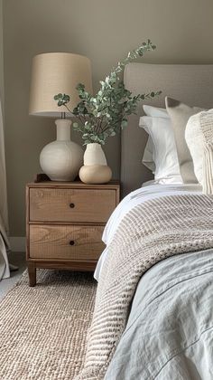 a bed room with a neatly made bed and two vases on top of it