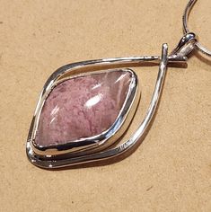 I created this abstract design to highlight the beauty of this Pink Rhodochrosite stone in a way to accent its natural character. This Sterling Silver Pendant is about 1-1/2 inches long and 7/8 inches wide. It has a 22 mm x 14 mm freeform parallelogram shaped and cut Rhodochrosite natural stone.   A freind of mine cut shaped and polished this stone for me.  I am including a 18 inch Sterling Silver mm 8 sided Snake Chain so your pendant can be worn right away. Pink Rhodochrosite, Pendant With Chain, Snake Chain, Sterling Silver Pendant, Sterling Silver Pendants, Abstract Design, Natural Stone, Silver Pendant, Natural Stones