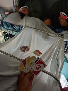 people playing cards in an inclosure on a hospital bed with the covers pulled down