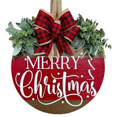 a wooden sign that says merry christmas hanging on a door hanger with greenery