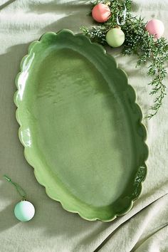 an oval green platter sitting on top of a bed next to eggs and greenery