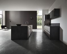 a modern kitchen with black cabinets and counter tops in an open space that looks out onto the outdoors