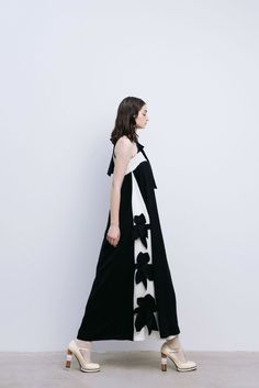 This dress is made from two types of fabric: black, denser fabric, and white, soft and smooth fabric. Every detail of this dress is imbued with style and sophistication. The combination of black and white creates an elegant contrast that catches the eye. The dress with open shoulders has a loose fit and widens towards the bottom due to the large amount of fabric and pleats. There is a lining. This dress ensures a perfect fit thanks to the wide elastic band at the chest and a shoulder tie that ca