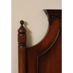 the headboard and foot board of a wooden bed with a white wall in the background