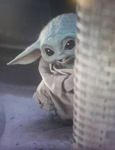 a baby yoda is sitting in front of a pole